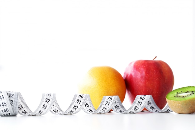 Naranja, kiwi y manzana rodeados de una cinta métrica