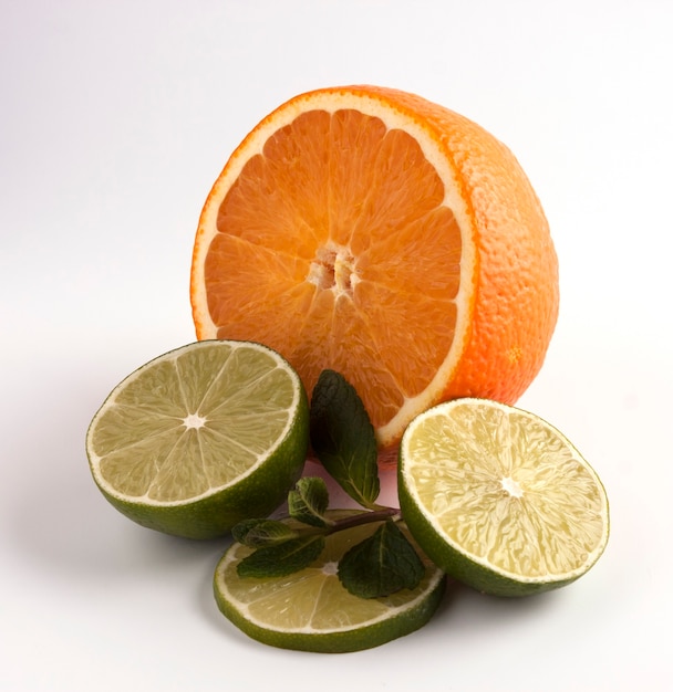 Naranja y lima cortada por la mitad con menta. Fruta cítrica aislado sobre fondo blanco.