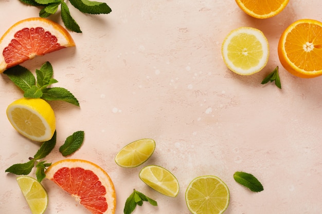 Naranja, limón, pomelo, mandarina y lima sobre fondo de mesa de hormigón o piedra rosa de moda