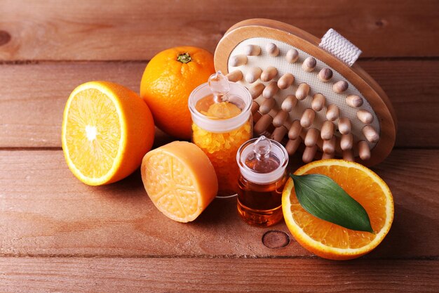 Foto naranja madura con botellas de sal de baño y barra de aceite esencial de jabón y cepillo de madera sobre fondo de madera