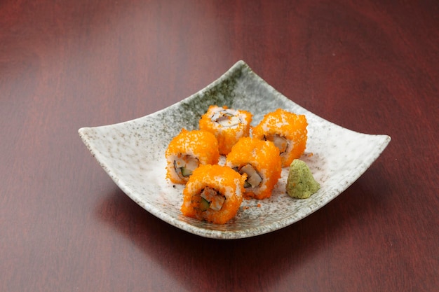 Naranja Maki de California servida en un plato aislado en la vista lateral de la mesa de madera de la comida de Singapur