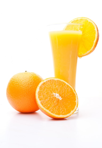 Una naranja y media cerca de un vaso de jugo de naranja