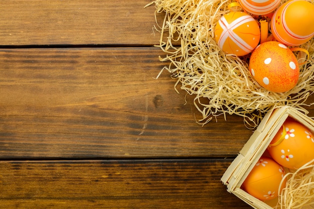 La naranja modeló los huevos de Pascua en una jerarquía en una tabla de madera marrón. Vista superior, copia espacio.