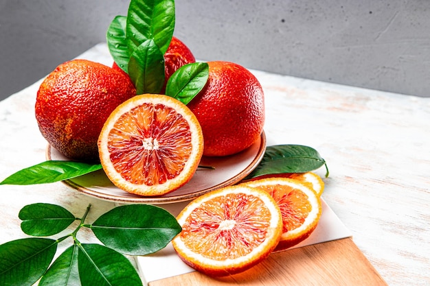 Naranja roja cortada en rodajas y todo sobre una tabla de cortar de madera de cerca