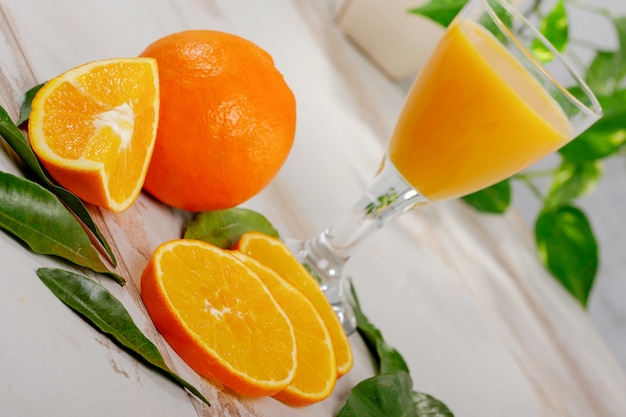 Naranja y vaso de jugo de naranja en mesa de madera blanca