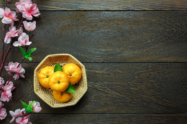 Naranja de la visión superior, hoja, cesta de madera, flor del ciruelo en fondo de madera de la tabla con el espacio de la copia.