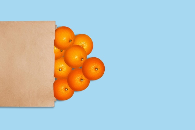 Naranjas en una bolsa de papel Sobre un fondo azul.