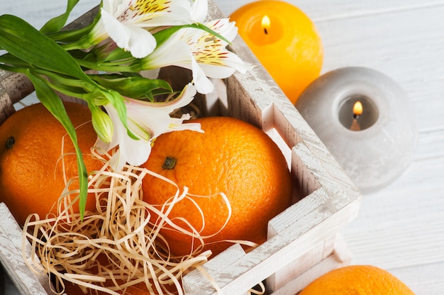 Naranjas en caja de madera, velas encendidas