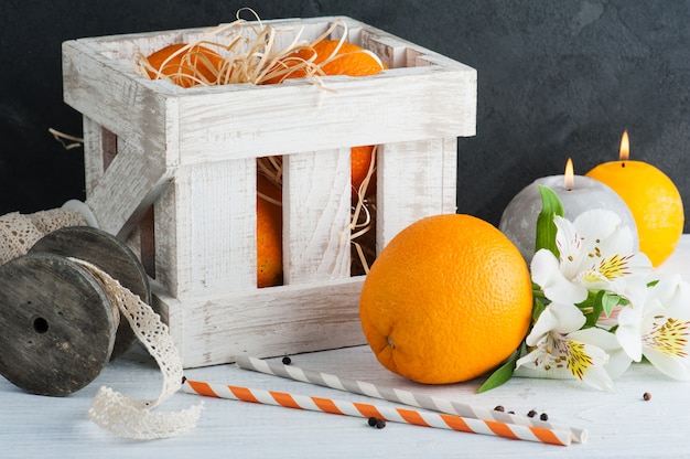 Naranjas en caja de madera, velas encendidas