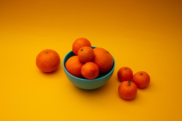 Naranjas cítricas en un recipiente sobre un fondo amarillo