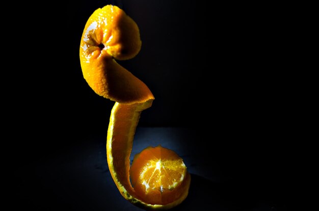 Naranjas en cuenco de madera con fondo negro.