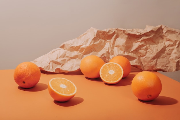 Naranjas esparcidas sobre una mesa de jengibre sobre un fondo de papel kraft arrugado.