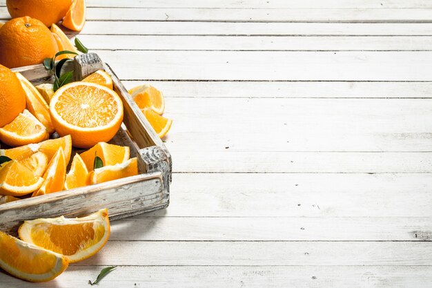 Naranjas frescas en una caja. Sobre una mesa de madera blanca.