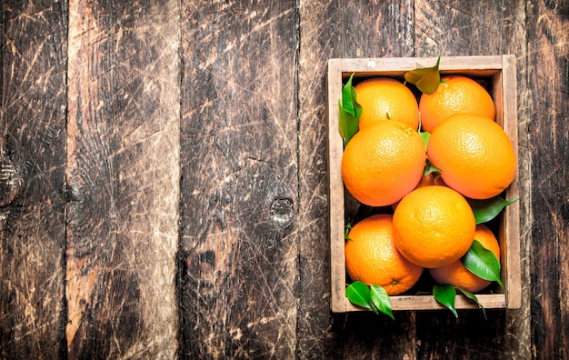 Naranjas frescas en una caja vieja. Sobre fondo de madera.