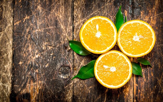 Naranjas frescas con hojas verdes. Sobre fondo de madera.