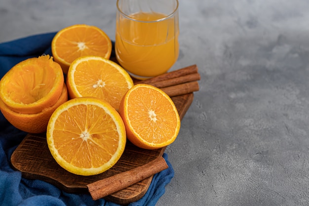 Naranjas frescas maduras en rodajas por la mitad sobre un paño azul. Decorado con palitos de canela, semillas de clavo y hojas verdes.