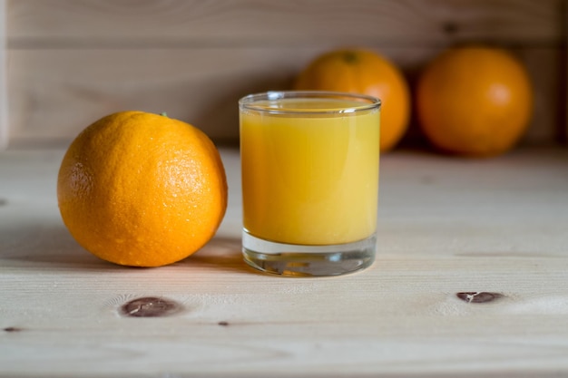 Naranjas frescas sobre la mesa y un vaso de jugo.
