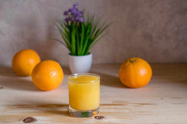 Naranjas frescas sobre la mesa y un vaso de jugo.