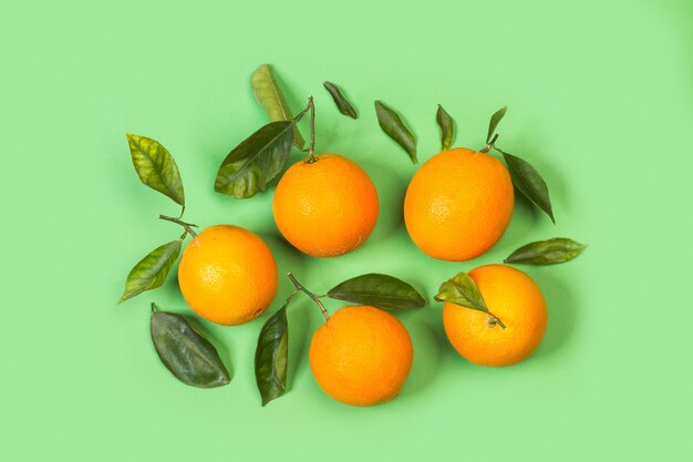 Naranjas con hojas sobre un fondo verde