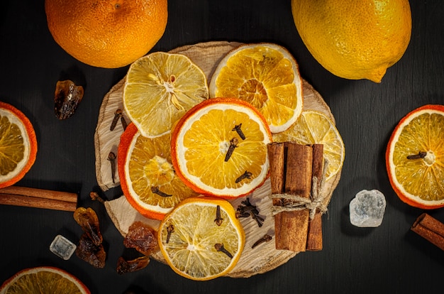 Naranjas y limones frescos y secos sobre superficie negra.