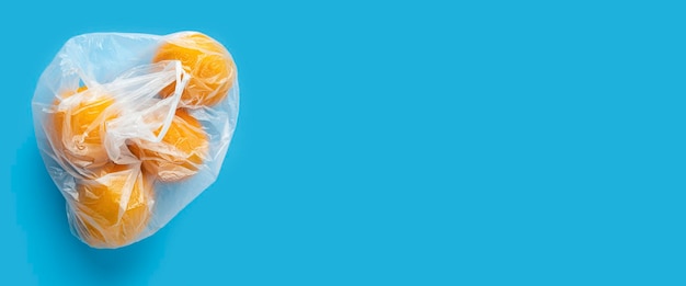 Naranjas maduras frescas en una bolsa de plástico transparente sobre un fondo azul Vista superior plano Lay Banner