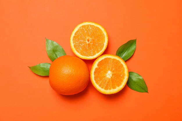 Naranjas maduras y hojas sobre fondo de color. Espacio para texto