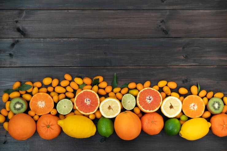 Las naranjas, las mandarinas, el kiwi, los limones y la lima cítricos se encuentran sobre un fondo negro de madera de las tablas.