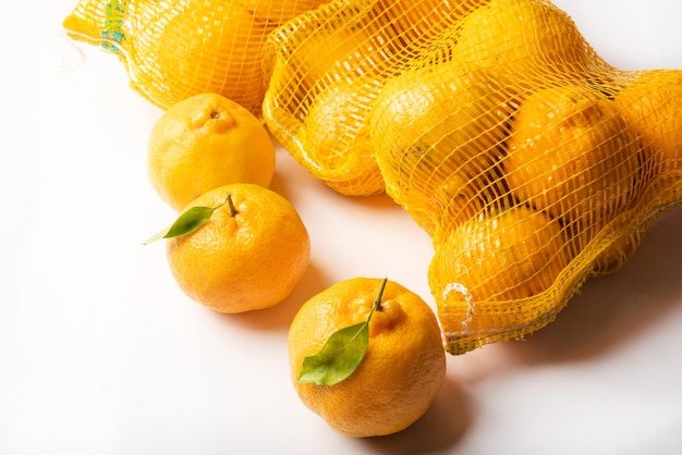 Naranjas Ponkan sueltas y en una red sobre fondo blanco Vista superior