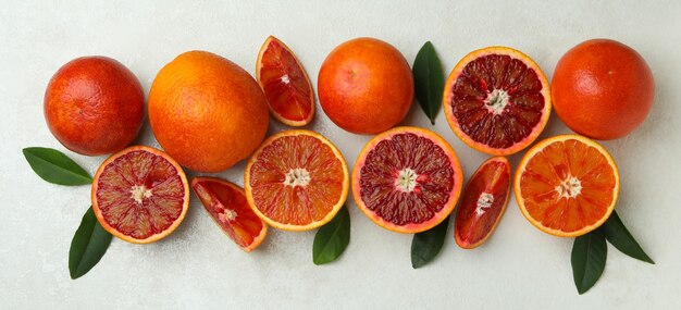 Naranjas rojas y hojas en blanco con textura