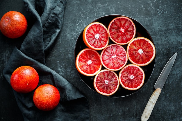 Naranjas de sangre cortadas en un plato sobre un fondo negro