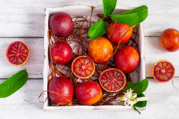 Naranjas de sangre jugosas, enteras y medias, sobre un fondo blanco