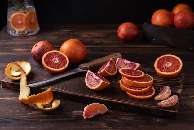 Naranjas sanguinas cortadas por la mitad y en rodajas sobre una tabla para cortar