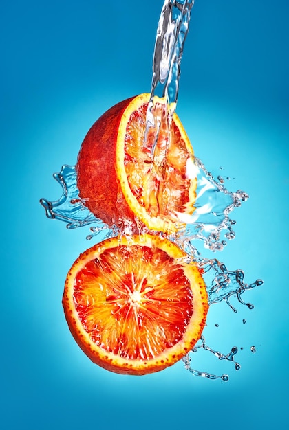 Naranjas sicilianas con un chorrito de agua sobre un fondo azul Levitación de naranjas