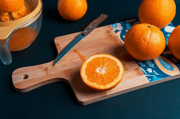 Naranjas en un tablero de cocina y extractor de jugo en un fondo oscuro