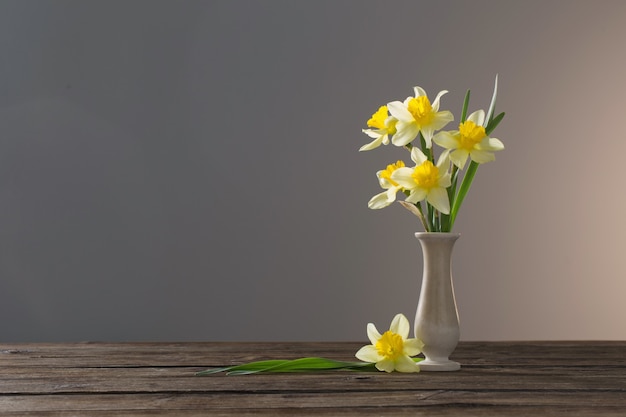 Narciso amarelo em um vaso na mesa de madeira na superfície escura