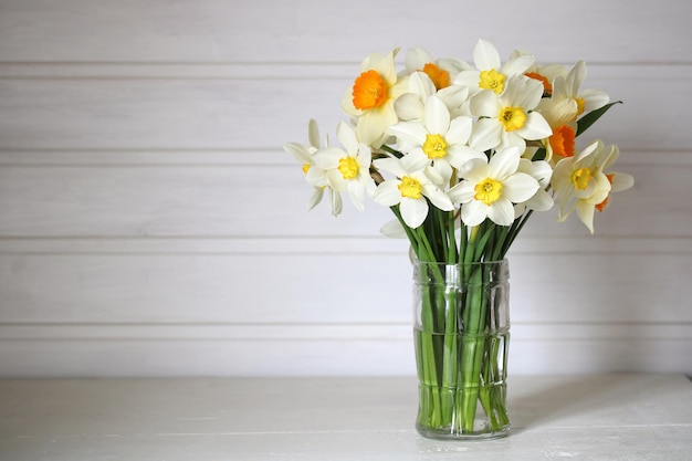 Narcisos em uma caneca de vidro sobre uma mesa branca em uma casa de campo interior flores de primavera