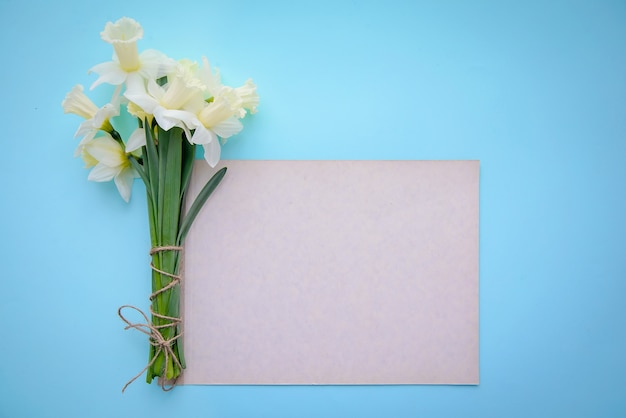 Narcisos sobre fondo azul con un trozo de papel con espacio de copia