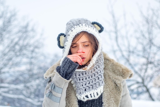 Nariz escorrendo da gripe resfriada no inverno mostrando uma mulher doente espirrando no parque de inverno