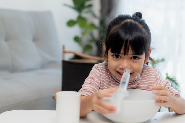 La nariz de lavado nasal de solución salina de niña asiática en casa