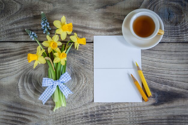 Narzissen- und Muscariblumen mit Karte und Tasse Tee