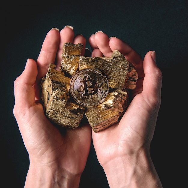 Nas mãos de peças de ouro e bitcoin. conceito de mineração rentável