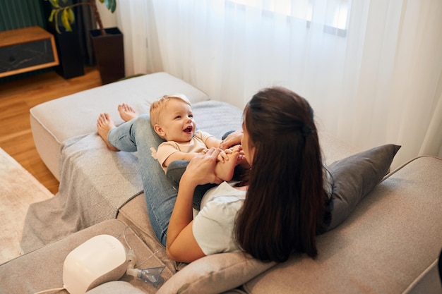 Nas pernas da mulher Mãe com o seu filho pequeno está em casa no quarto doméstico