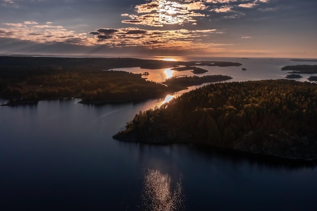 Nascer do sol acima das ilhas rochosas cobertas de árvores no arquipélago no Lago Ladoga Karelia Rússia