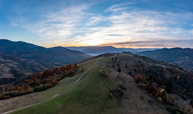 Nascer do sol brilhante em altas montanhas cobertas de floresta de outono