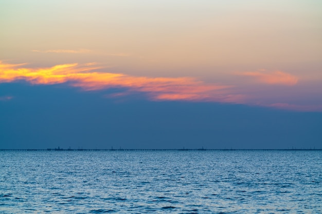 Nascer do sol colorido no mar, plataformas de petróleo à distância