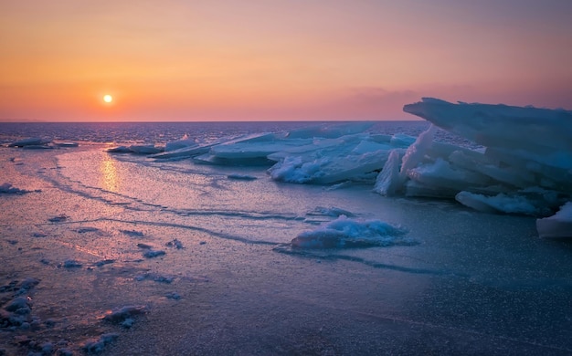 Nascer do sol e mar congelado Linda paisagem de inverno com lago e sol vermelho na manhã Alvorada