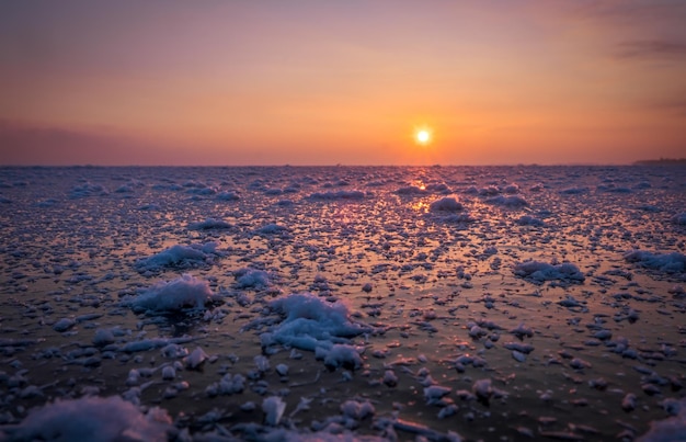 Nascer do sol e mar congelado Linda paisagem de inverno com lago e sol vermelho na manhã Alvorada