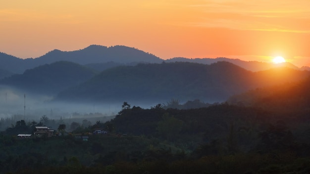 Foto nascer do sol místico dourado e paisagem e vila enevoada