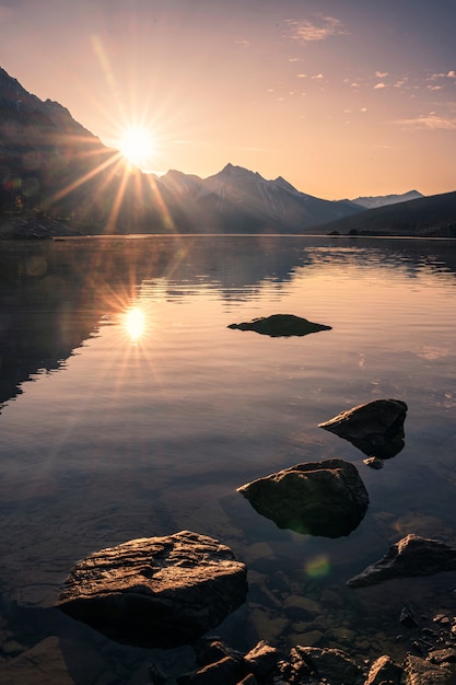 Foto nascer do sol na montanha rochosa com pedras no lago medicine no parque nacional de jasper