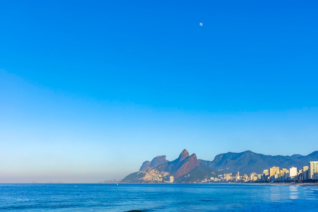 Nascer do sol na praia de Ipanema, no Rio de Janeiro, com a lua no céu